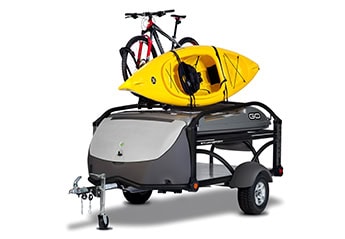 Compact SylvanSport GO camping trailer with kayak and bike on top, ideal for outdoor adventures.