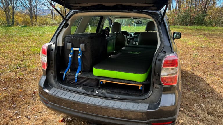 Self-inflating camping mattress in vehicle trunk for outdoor adventures.