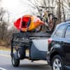 DuraDeck trailer carrying kayak and mountain bike on road.