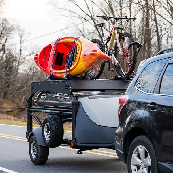 DuraDeck trailer carrying kayak and mountain bike on road.