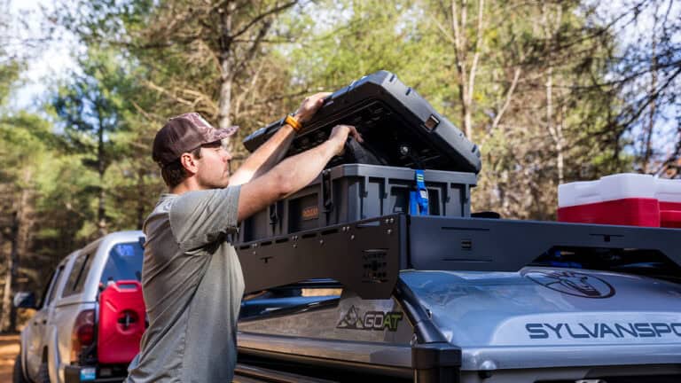 Person installing DuraDeck on SylvanSport GOAT trailer for outdoor use.