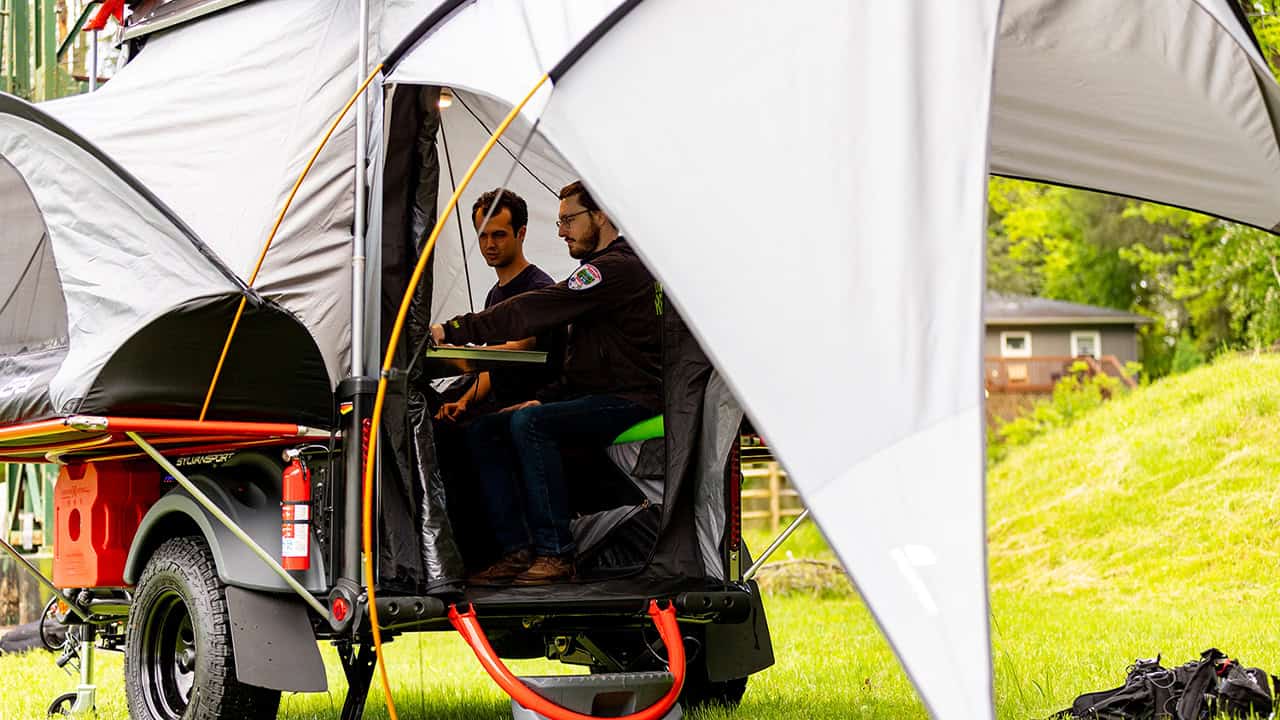 Compact SylvanSport GO trailer with tent setup for outdoor adventures.
