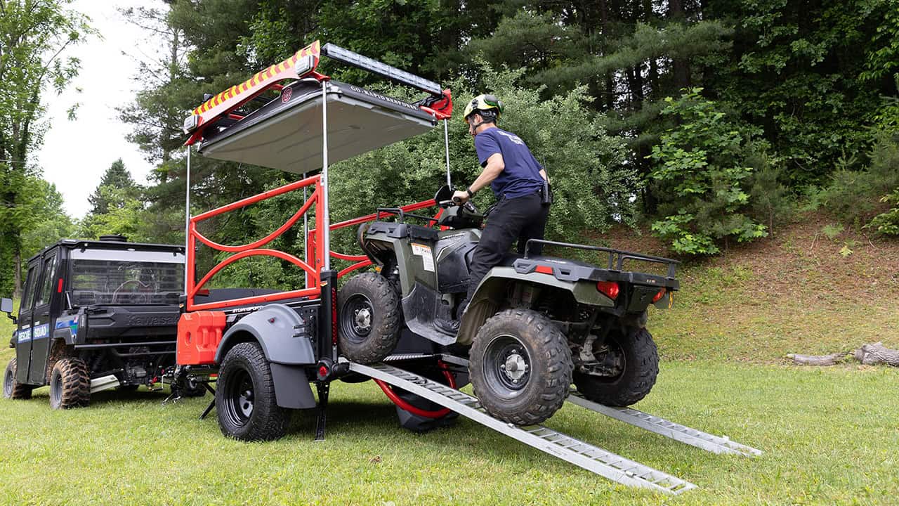 Outdoor adventure trailer with ATV loading ramp and canopy.