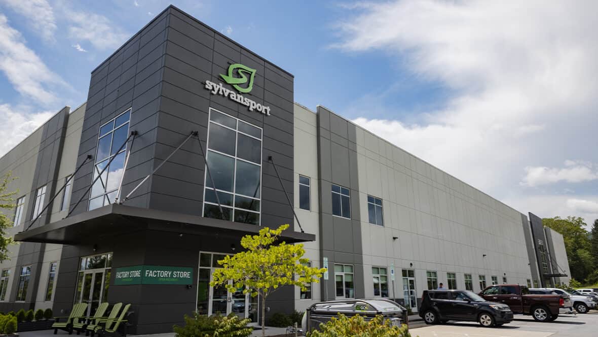 Modern SylvanSport building with logo, factory store, and parking lot.